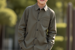 a-young-boy-in-a-suit-standing-in-front-of-a-fence